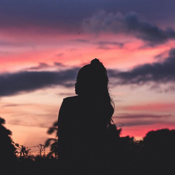 Silhouette of a person stretching against a vibrant sunrise.